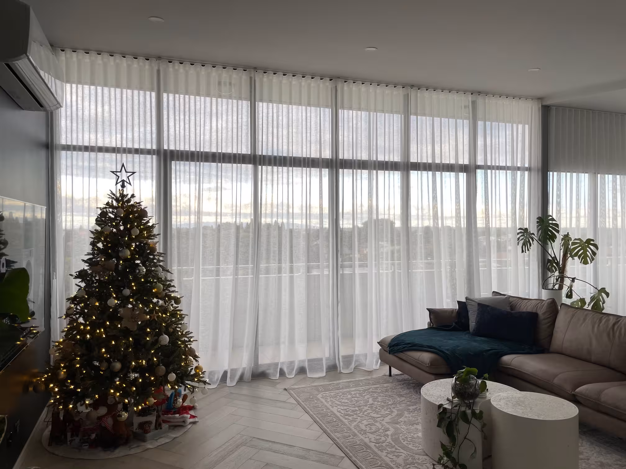 Sheer floor-to-ceiling curtains across a wall of windows in a bright, modern living room